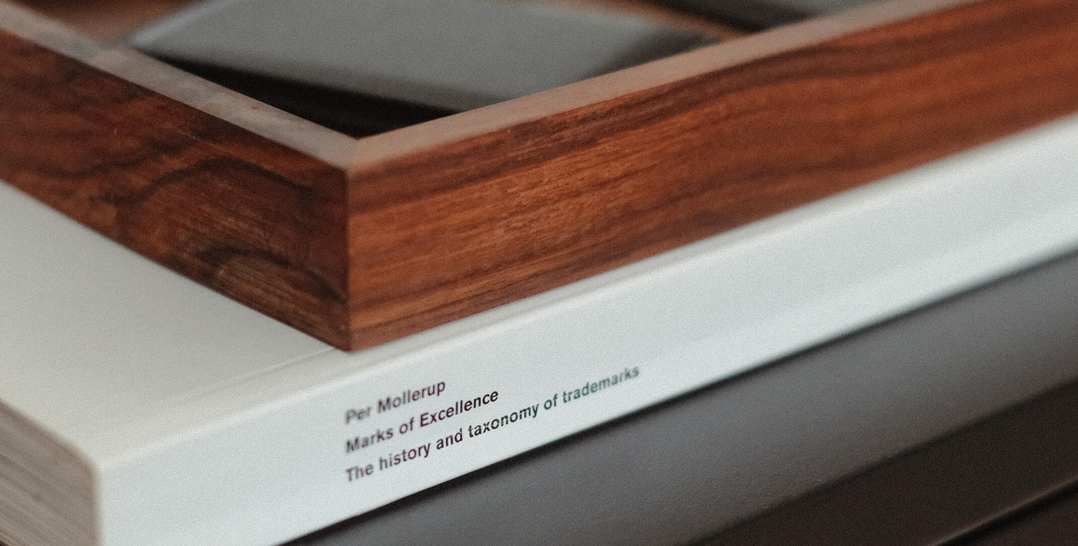 A photograph of Ben sitting in an urban area and looking off-camera. He's wearing winter clothes: a beanie hat, sunglasses, a woolly jumper and a technical coat.